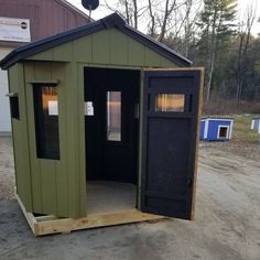 a small green shed sitting on top of a dirt field