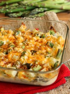 a casserole dish with asparagus and cheese in it on a red towel