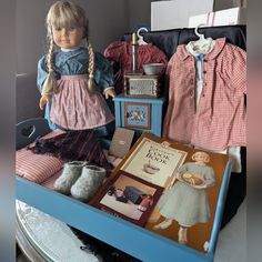 the doll is sitting next to other dolls and books