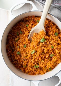 a pot filled with rice and garnished with cilantro on the side