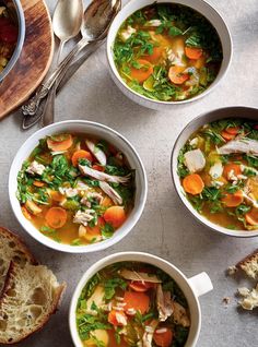 four bowls filled with soup next to slices of bread