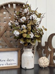 a vase filled with cotton sitting on top of a table next to a wooden sign