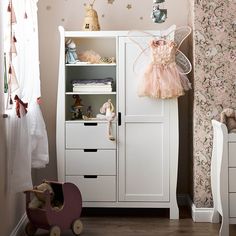 there is a white cabinet in the room with pink decorations on it and a teddy bear next to it