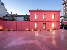 an empty courtyard with pink walls and lights in the windows at dusk, surrounded by tall buildings