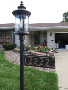 a lamp post in front of a house with a mailbox and flowers on it