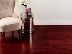 a chair sitting on top of a wooden floor next to a vase with flowers