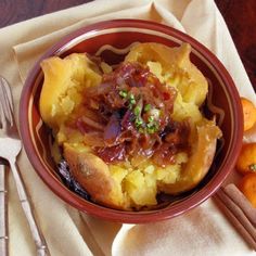 a bowl filled with food sitting on top of a table next to oranges and silverware