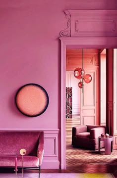 a living room with pink walls and purple couches in the center, along with a mirror on the wall