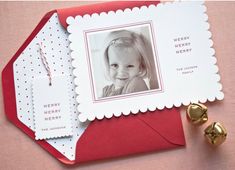 a red envelope with a christmas card and two gold bells