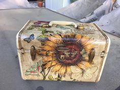 an old suitcase with a sunflower painted on it