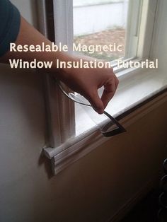 a hand holding a window seal in front of a window with the words resealable magnetic window insulation editorial