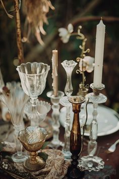 a table topped with lots of glass vases and candlesticks next to each other