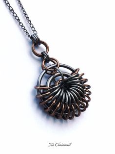 a necklace that has been made out of metal and is hanging from a silver chain