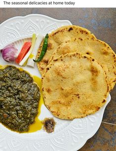 three flat breads on a white plate with green sauce and sliced vegetables next to each other