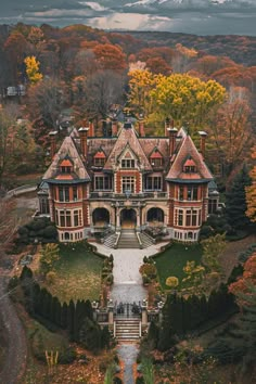 an aerial view of a large house in the middle of trees with fall foliage around it