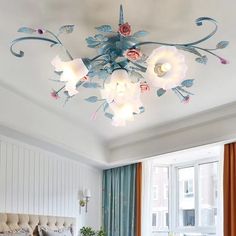 a bed room with a neatly made bed next to a large window and a chandelier