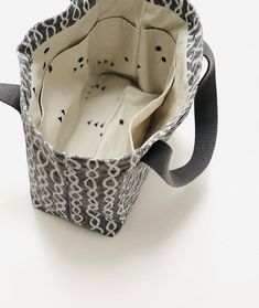 the inside of a bag with an animal print pattern and black handles, on a white surface