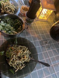 three bowls of food on a table with wine glasses and utensils next to them