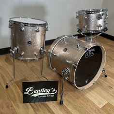 a silver drum set sitting on top of a hard wood floor next to a sign