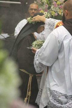 the priest is placing flowers on the bride's veil