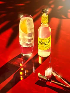 a bottle of booze sitting next to a glass filled with ice and lemon wedges