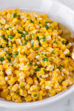 a white bowl filled with corn and garnished with parsley