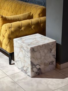 a marble block sitting on top of a floor next to a yellow couch