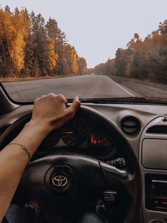 a person driving a car on a road with trees in the background