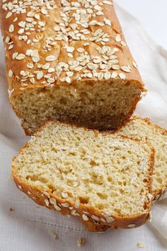 a loaf of bread sitting on top of a white towel next to a slice of bread