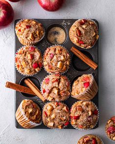 muffins with apples and cinnamon on top in a muffin tin next to other muffins