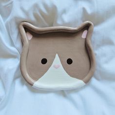 a brown and white cat shaped dish on a bed