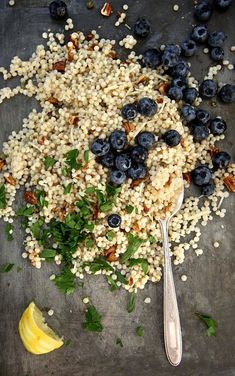 blueberries and other food are on a tray with a spoon next to some lemon wedges