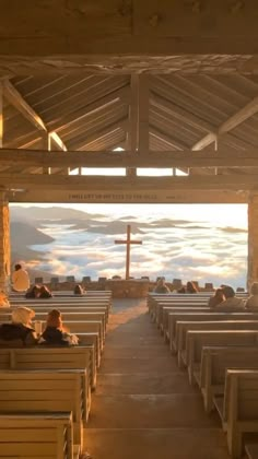 people are sitting at benches in front of the ocean and cross on top of it