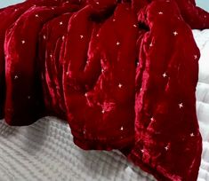 a red comforter on top of a bed with white sheets and star print pillows