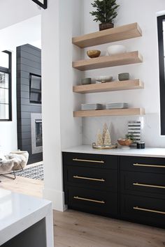 a kitchen with black cabinets and white counter tops, gold trim on the drawers and shelves