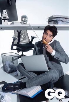 a man sitting on the floor with a laptop and donut in front of him