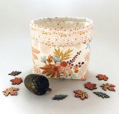 a small bag with flowers and leaves on the ground next to a piece of wood