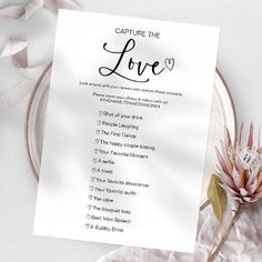 a white card with the words capture the love on it next to a pink flower