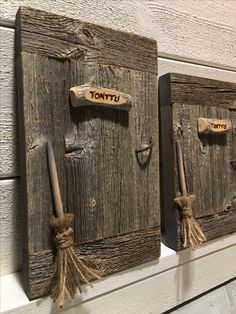 two wooden plaques with brooms and name tags attached to the sides, hanging on a wall