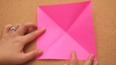 someone is making a pink origami piece with one hand and the other hand