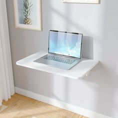 a laptop computer sitting on top of a white shelf next to a window in a room