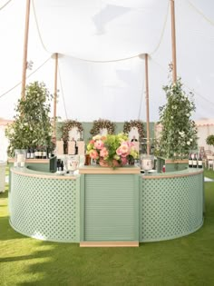 an outdoor bar with flowers and candles on the top is set up in front of a tent