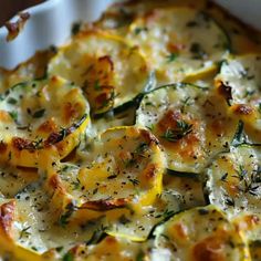 a casserole dish with zucchini, cheese and herbs in it on a white plate