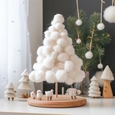 a white christmas tree with pom - poms on it and other decorations in the background