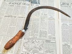 an old knife is laying on top of a newspaper