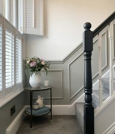 a vase filled with flowers sitting on top of a table next to a stair case