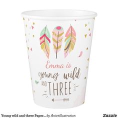 a paper cup with colorful feathers on it and the words young wild and three written below