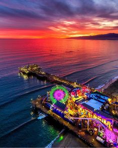 an aerial view of the boardwalk and ferris wheel at night with colorful lights on it