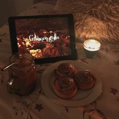 a table topped with donuts next to a jar of cinnamon syrup and a tablet