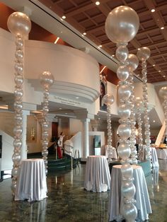 a room filled with tables covered in white tablecloths and balloons hanging from the ceiling